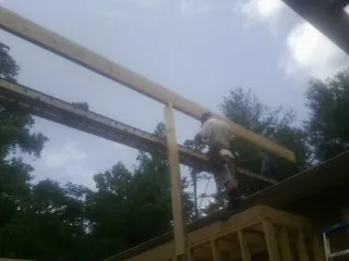 Carpenter setting a ridge beam over a new addition frame — Ice Dam Removal by Roofing Brothers in Musselshell