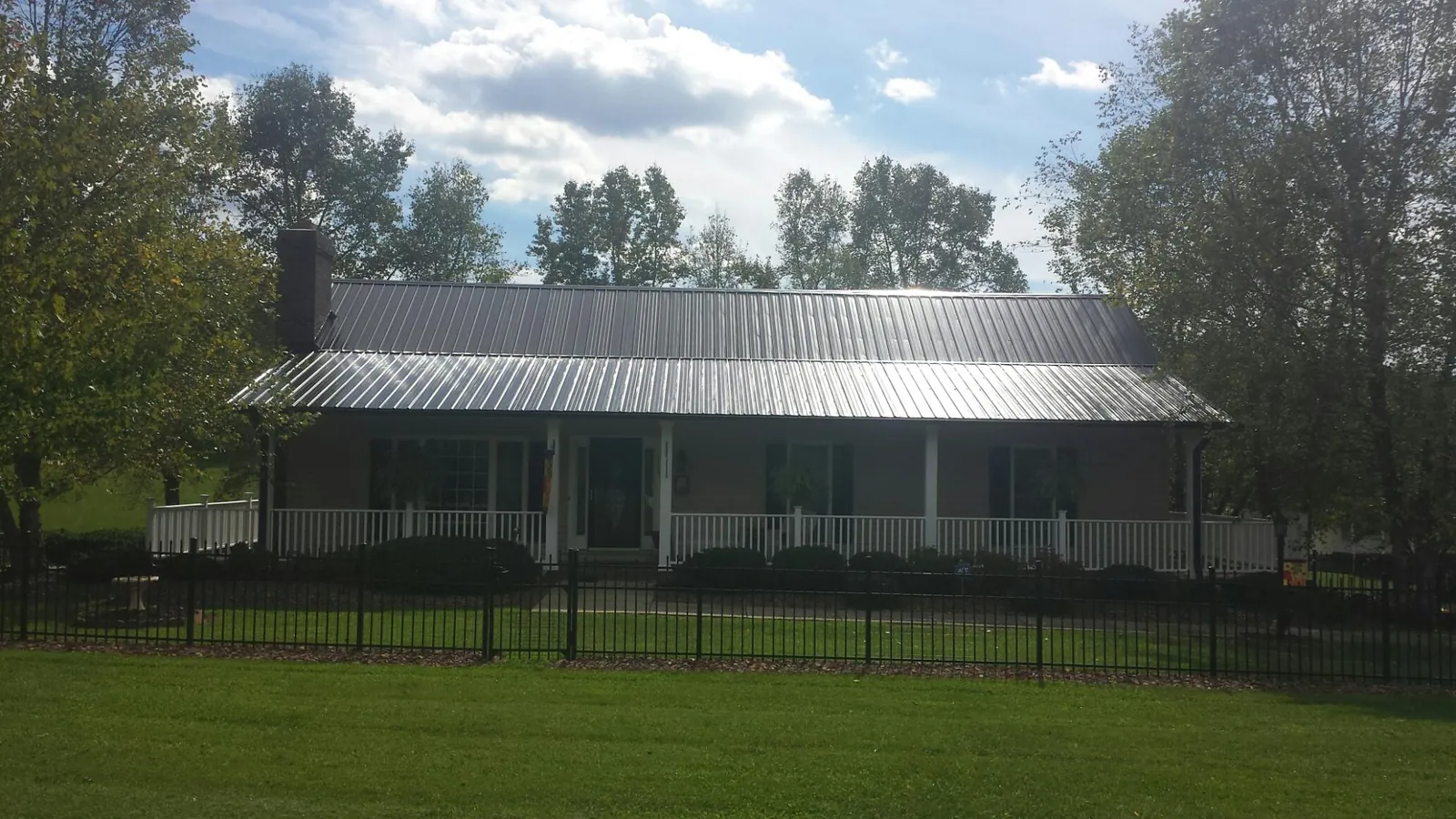 Gray metal roof on a brick ranch with a full width front porch — Gutter Guard Installation work by our crew in Musselshell