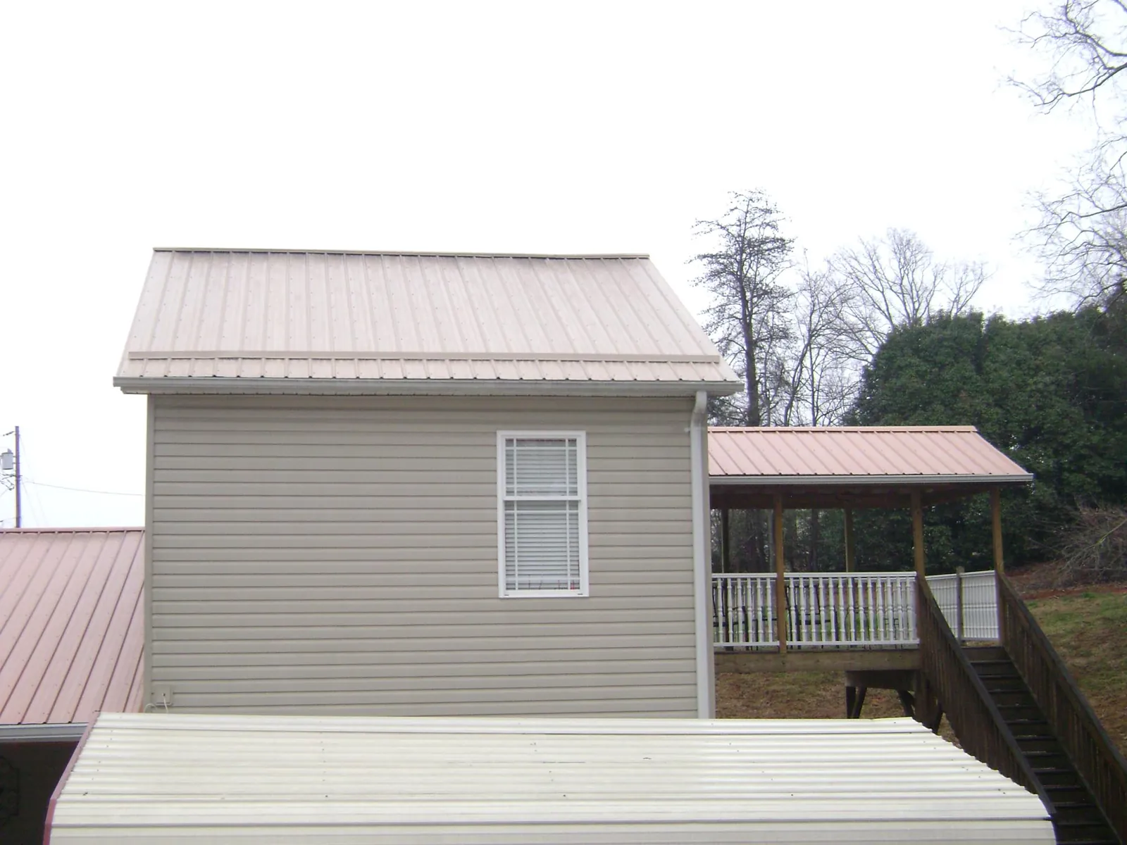 Tan metal roofs on a two story addition and attached porch, from a Roof Replacement job in Musselshell