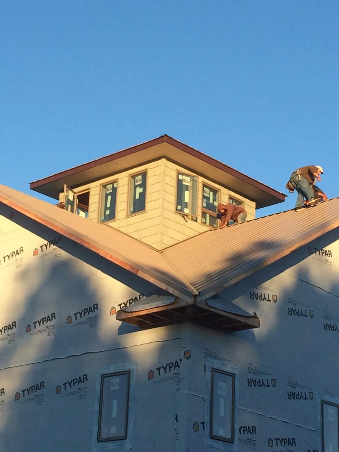 Roofers working around a rooftop cupola on a new metal roof at sunset — Roof Waterproofing in Musselshell by Roofing Brothers
